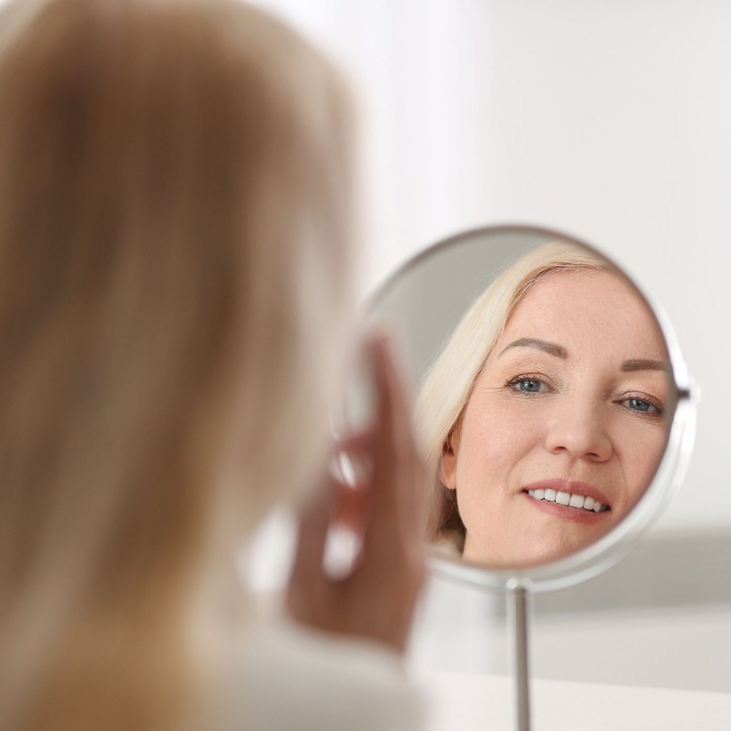 mature women looking in a mirror at her skin